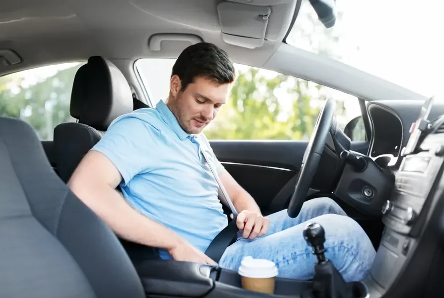 Occupant seated in a passenger car with the seat belt fastened across chest and lap