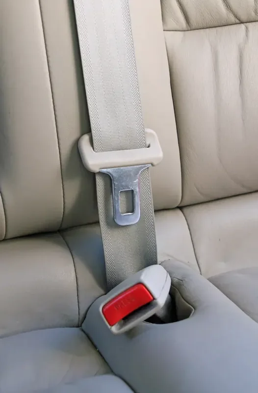 Three-point seat belt routed diagonally across the backrest of a rear car seat