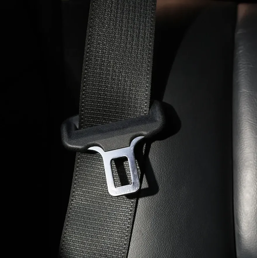 Detail of a metal seat belt latch plate on black webbing